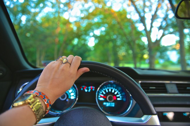 Woman's hand on the steering wheel driving a car