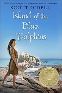  Book cover of Island of the Blue Dolphins by Scott O'Dell - Girl in animal skins standing on a sea cliff with a wild dog