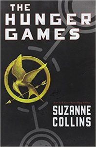 The Hunger Games book cover - black background with gray shapes and gold bird & arrow pin