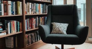 Reading chair in front of a full bookcase.