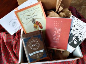 Book subscription box with a classic novel, tea tin, and desk calendar