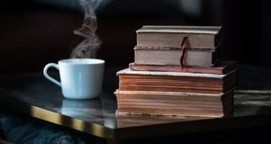 Stack of old books with steaming cup of hot tea