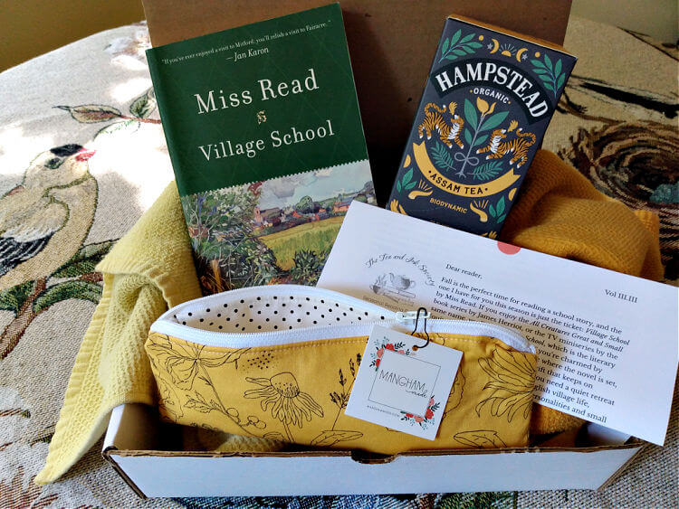 Book and tea subscription box with Village School by Miss Read, yellow-patterned pencil pouch, and box of Assam tea from Hampstead Tea Company.